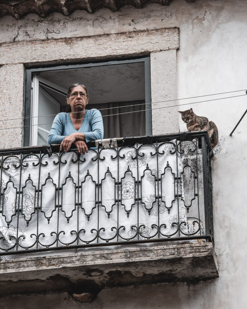 En dam på en balkong med sin katt i Lissabon